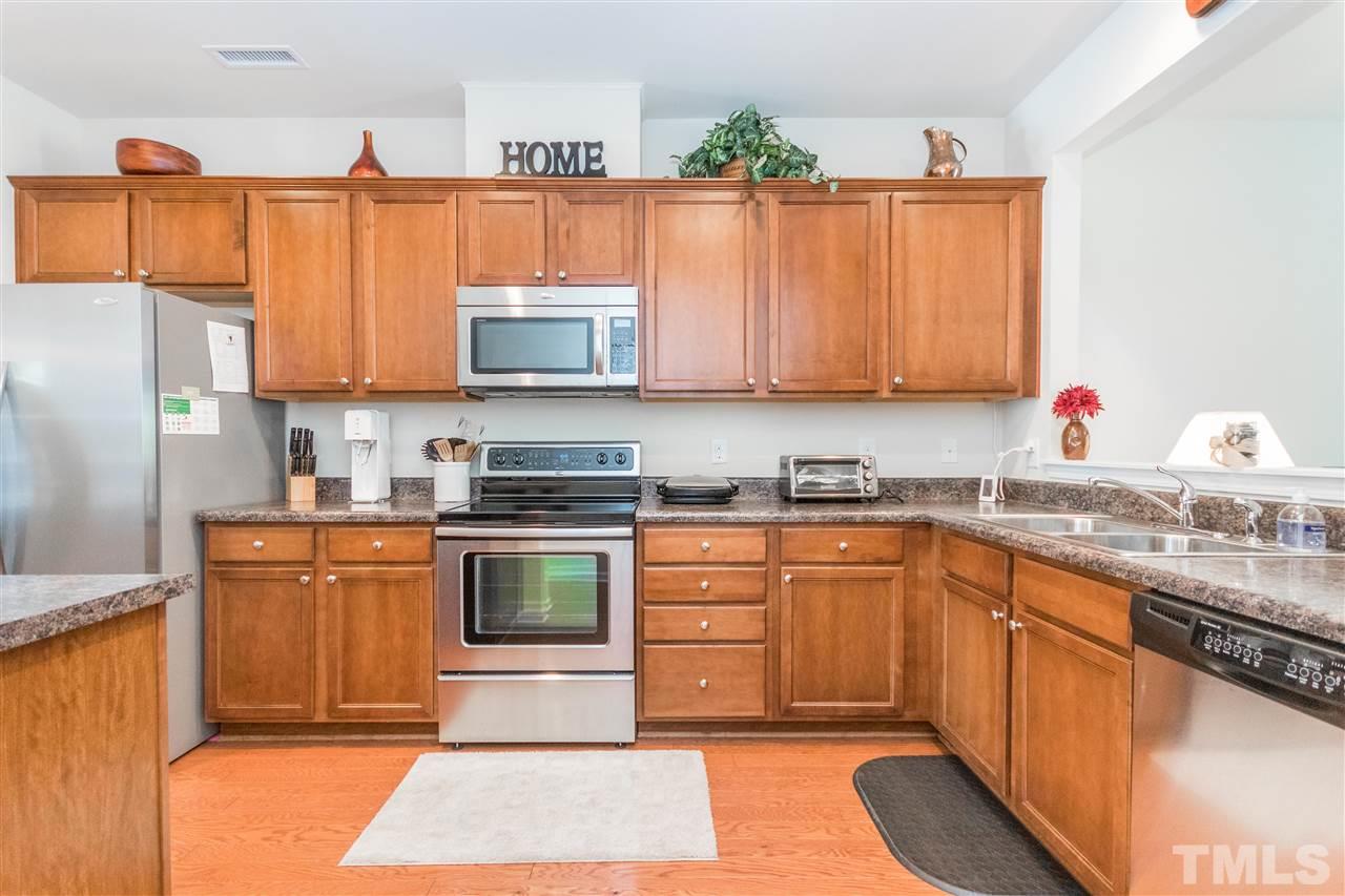 2960 Berkeley Springs Place Raleigh, NC 27616 - Photo 5 of 14 a kitchen with stainless steel appliances granite countertop a stove a sink dishwasher and a refrigerator with wooden cabinets