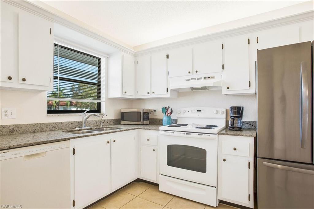 a kitchen with granite countertop white cabinets white appliances and sink