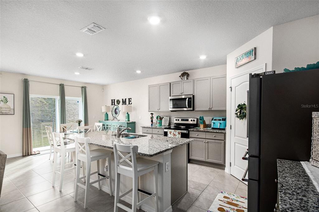 3027 Beau Loop Tavares, FL 32778 - Photo 11 of 30 a kitchen with stainless steel appliances a dining table chairs refrigerator and microwave