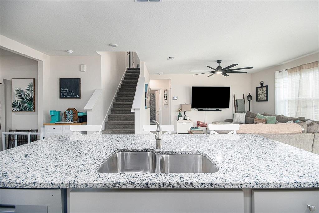 3027 Beau Loop Tavares, FL 32778 - Photo 12 of 30 a kitchen with granite countertop a sink and a white wooden cabinets