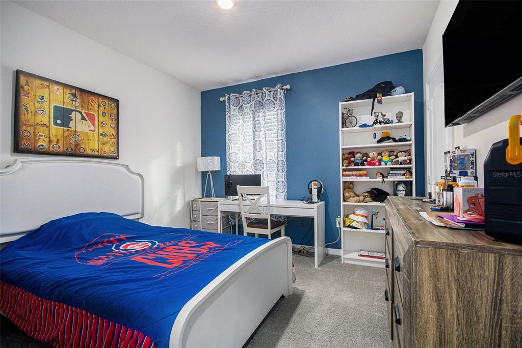 3027 Beau Loop Tavares, FL 32778 - Photo 14 of 30 a bedroom with a bed and a flat screen tv