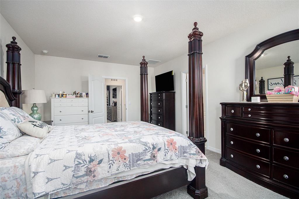 3027 Beau Loop Tavares, FL 32778 - Photo 19 of 30 a bedroom with a bed and a dresser