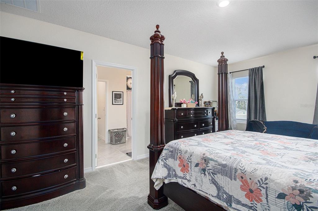 3027 Beau Loop Tavares, FL 32778 - Photo 21 of 30 a bedroom with a bed and a flat screen tv