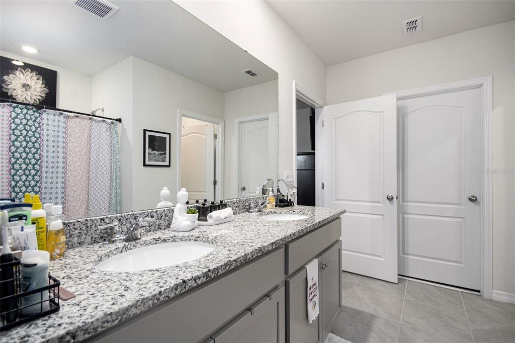 3027 Beau Loop Tavares, FL 32778 - Photo 22 of 30 a bathroom with a granite countertop sink and a mirror