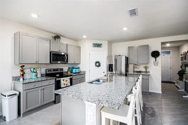 a kitchen with stainless steel appliances kitchen island granite countertop a stove top oven a sink dishwasher a refrigerator and cabinets with wooden floor