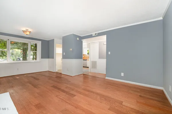 a view of an empty room with wooden floor and a window