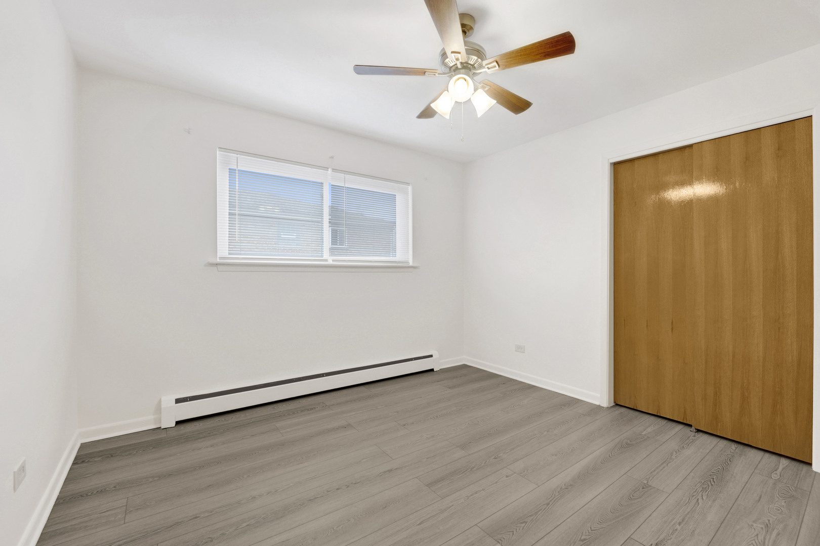 1608 Ogden Avenue, Unit 1E Downers Grove, IL 60515 - Photo 11 of 18 an empty room with wooden floor chandelier fan and windows