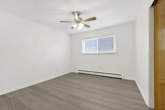 an empty room with wooden floor fan and windows