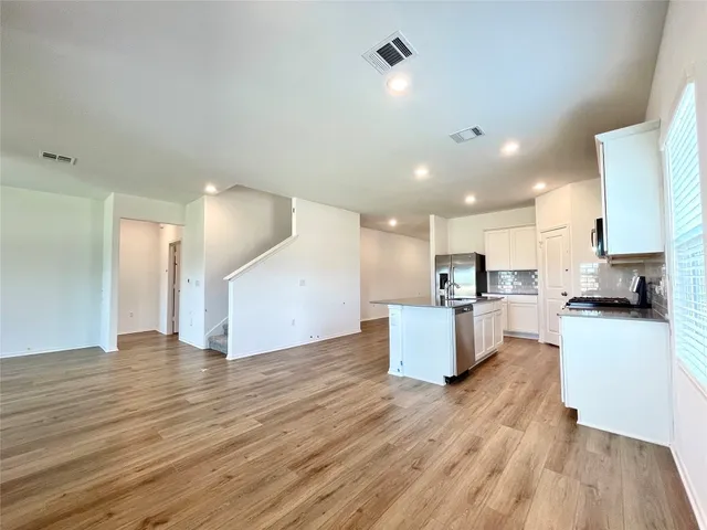 a view of kitchen with kitchen island wooden floors and white cabinets