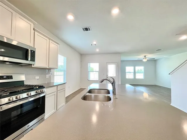a kitchen with stainless steel appliances kitchen island granite countertop a stove a sink and a microwave