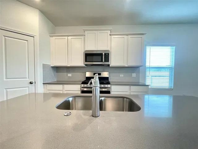 a kitchen with kitchen island a sink a stove and cabinets