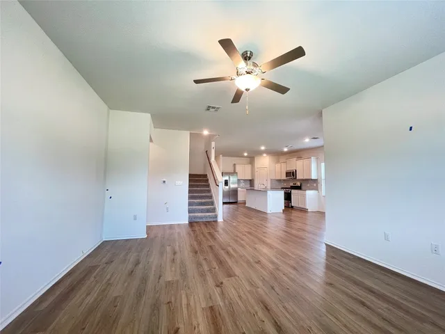 a view of a living room with wooden floor and ceiling fan