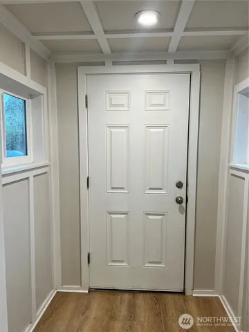 an empty room with wooden floor chandelier and windows