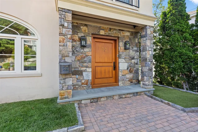a view of a brick house with large windows and a small yard