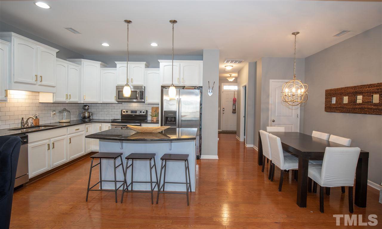 2441 Memory Ridge Drive Raleigh, NC 27606 - Photo 6 of 21 a kitchen with stainless steel appliances granite countertop a dining table chairs refrigerator sink and cabinets