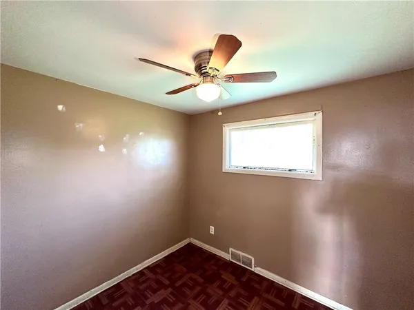 an empty room with a window and a fan