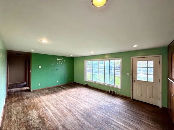 a view of an empty room with a window and wooden floor