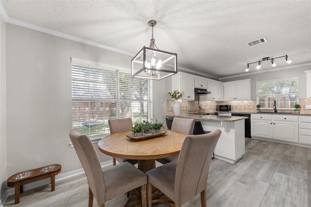 112 Briar Ridge Drive Hewitt, TX 76643 - Photo 5 of 15 Open-concept kitchen and dining area featuring light wood-finish flooring, white cabinetry, a granite countertop island, and a decorative light fixture