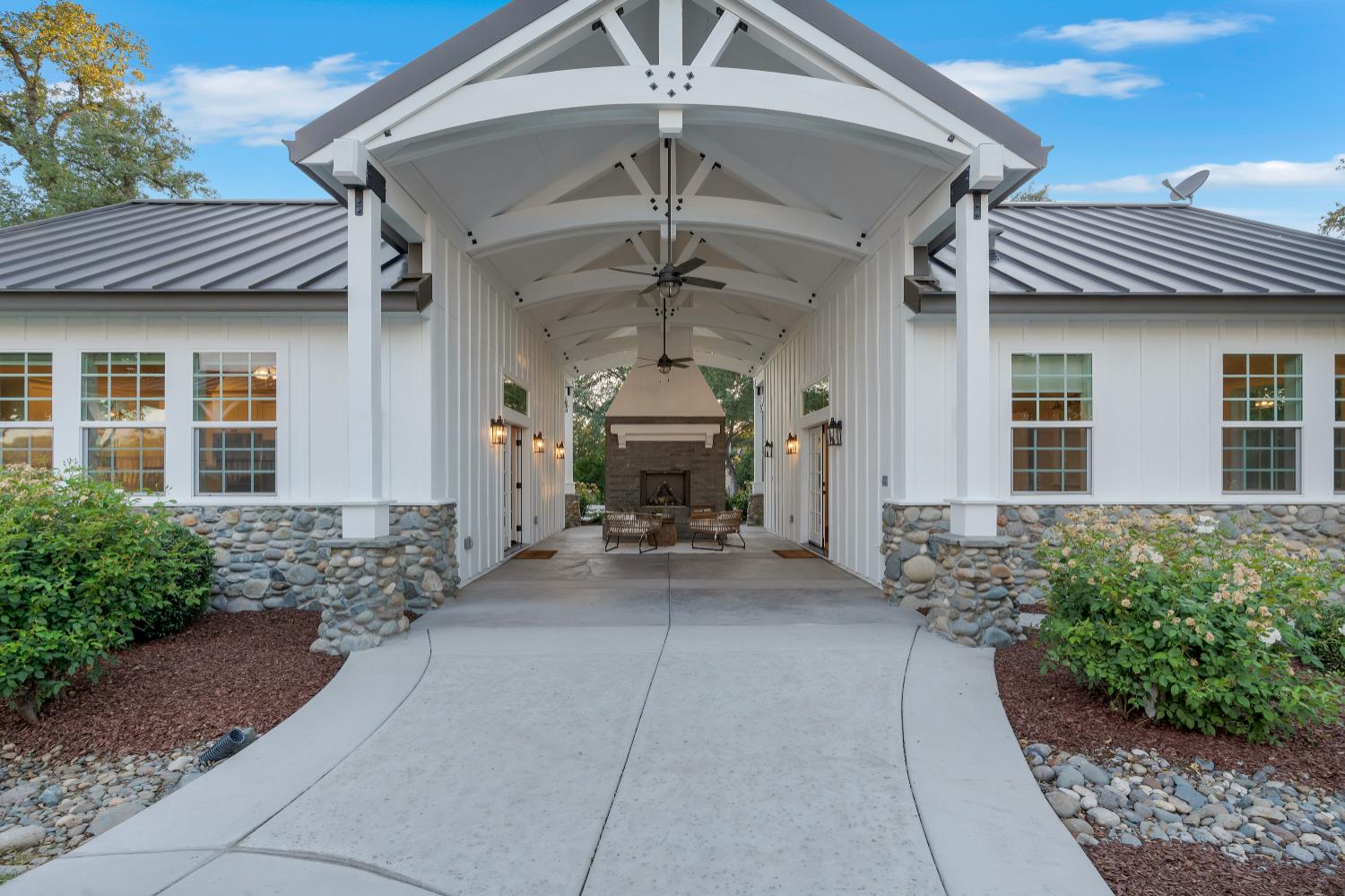 2905 Virginiatown Road Lincoln, CA 95648 - Photo 43 of 86 Expansive covered entry featuring a stone fireplace, exposed beam ceiling with ceiling fans, and board and batten siding
