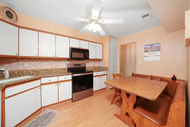 a kitchen with granite countertop a stove top oven a sink dishwasher a dining table and chairs with wooden floor