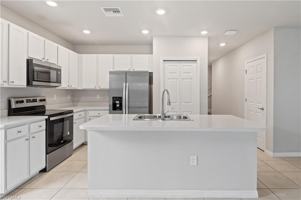 15245 Wildflower Circle Naples, FL 34119 - Photo 7 of 36 a kitchen with stainless steel appliances a refrigerator stove microwave and cabinets
