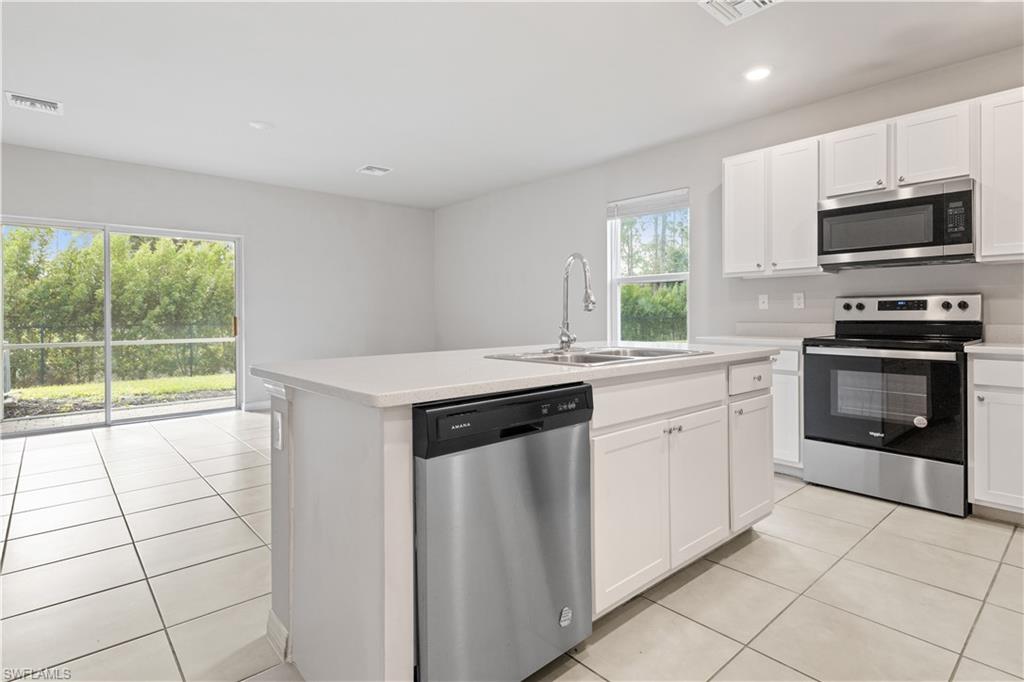15245 Wildflower Circle Naples, FL 34119 - Photo 9 of 36 a kitchen with stainless steel appliances a stove sink microwave and cabinets