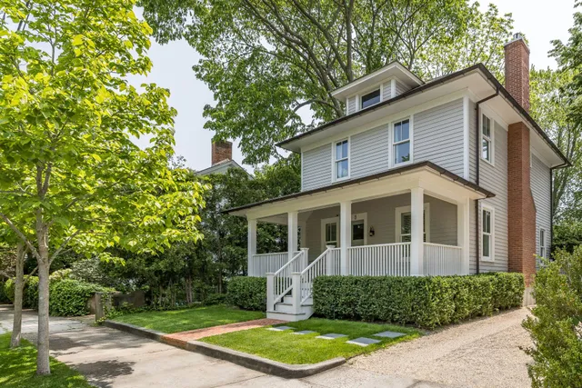 a view of a white house with large windows and a small yard