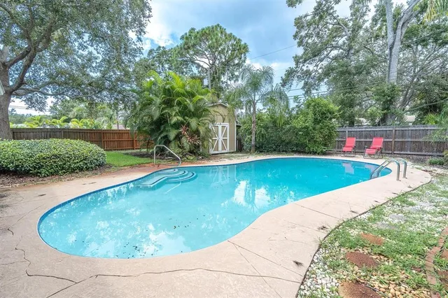 a view of a swimming pool with a yard and plants