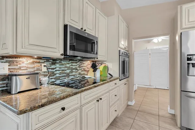 a kitchen with granite countertop white cabinets stainless steel appliances and a counter space