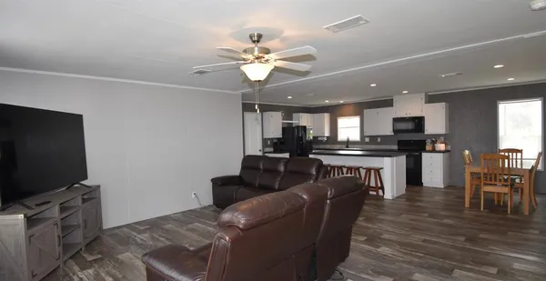 a living room with furniture a flat screen tv and kitchen view