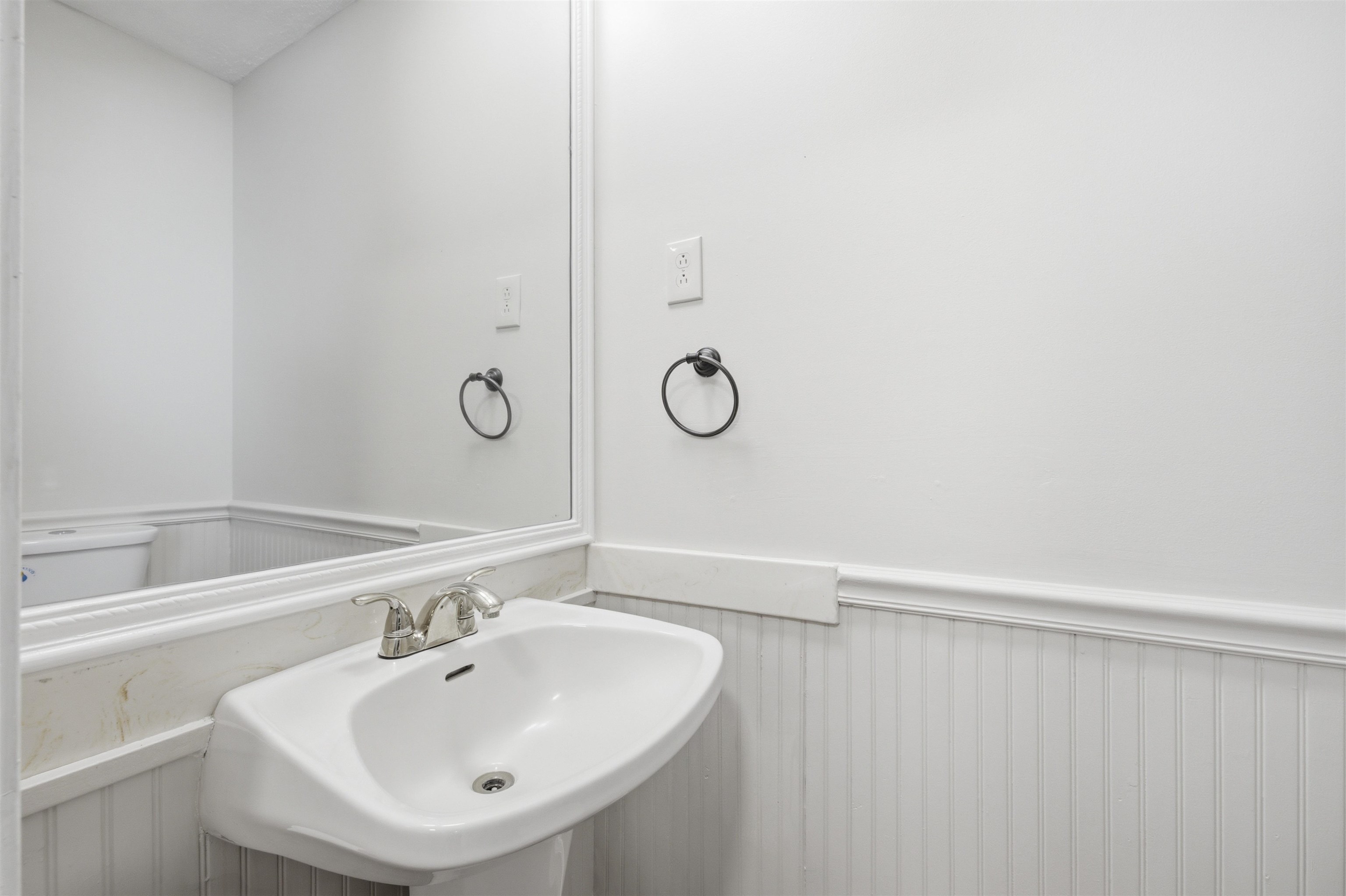 1370 North Reid Hooker Road Eads, TN 38028 - Photo 23 of 39 Pedestal sink with chrome faucet, framed mirror, and beadboard wainscoting