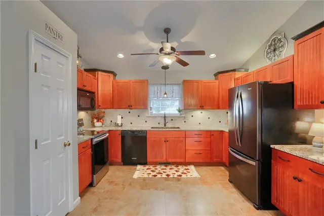 a kitchen with stainless steel appliances granite countertop a refrigerator a sink dishwasher a stove and white countertops with wooden floor