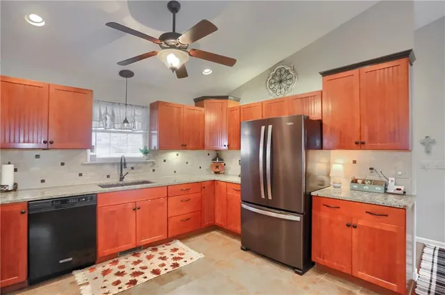 a kitchen with stainless steel appliances granite countertop a sink refrigerator and cabinets