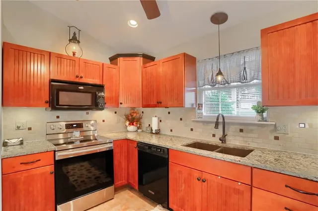 a kitchen with granite countertop a sink stainless steel appliances and cabinets