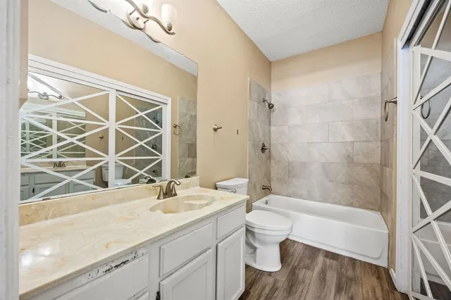 a bathroom with a granite countertop sink a toilet a mirror and shower