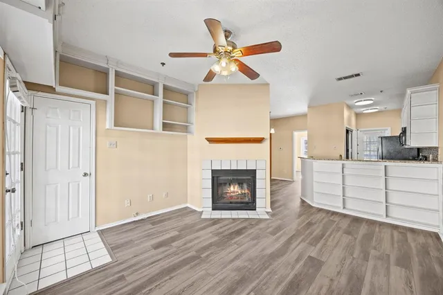 a view of a livingroom with a fireplace a ceiling fan and wooden floor