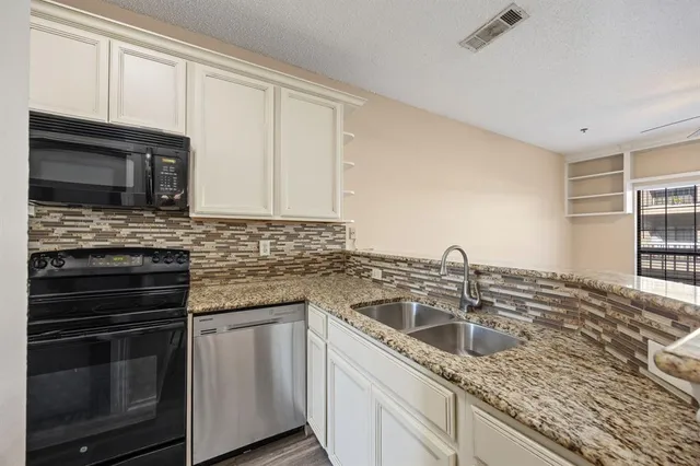 a kitchen with granite countertop a sink stainless steel appliances and cabinets