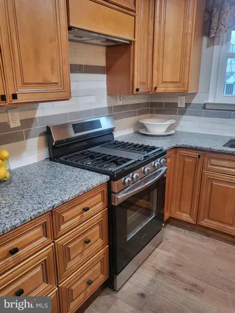 a kitchen with granite countertop wooden cabinets and a stove top oven