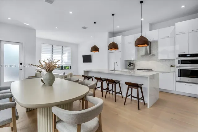 a kitchen with stainless steel appliances kitchen island granite countertop a sink a microwave a dining table and chairs