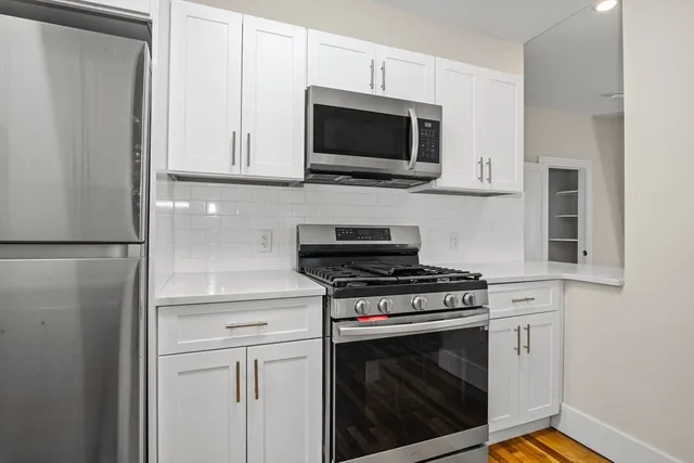 a kitchen with stainless steel appliances white cabinets and a stove top oven