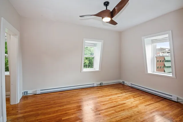 a view of empty room with wooden floor and fan