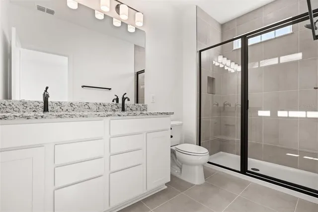 a bathroom with a granite countertop sink toilet mirror and shower