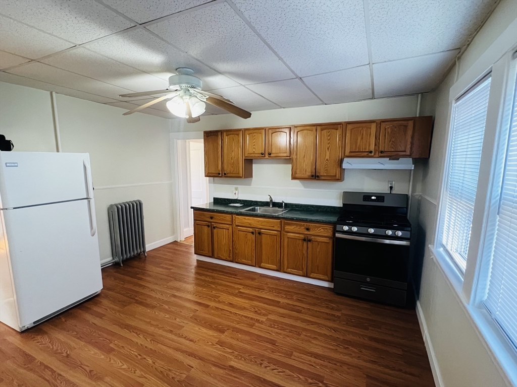 62 Westmore Road, Unit 2 Boston, MA 02126 - Photo 3 of 13 a kitchen with granite countertop wooden floors a stove and a refrigerator