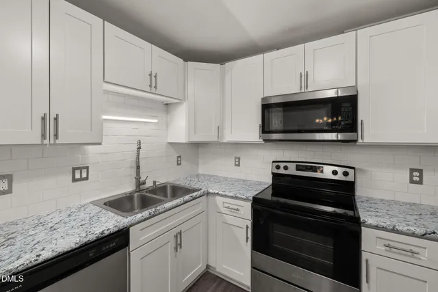 a kitchen with granite countertop white cabinets and stainless steel appliances