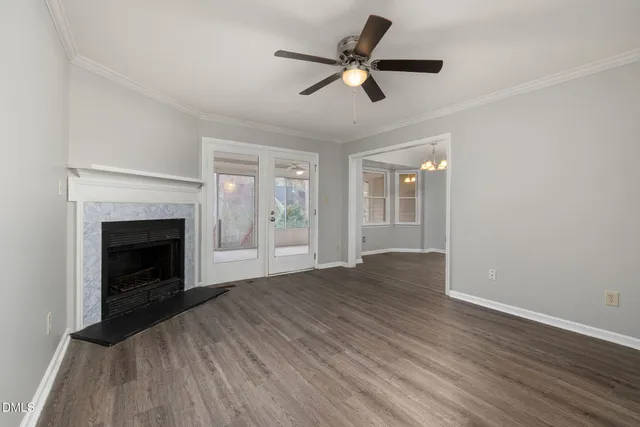 an empty room with wooden floor a ceiling fan and windows