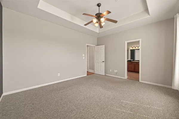 an empty room with chandelier fan and windows