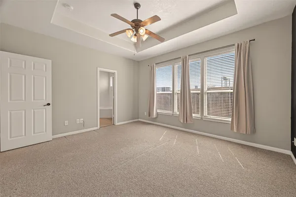 an empty room with chandelier fan and windows