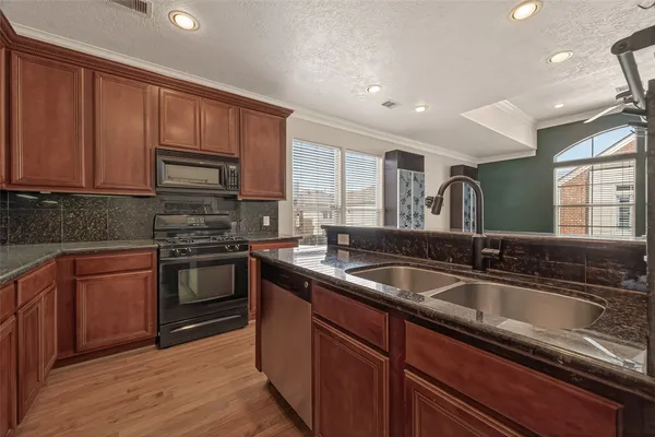 a kitchen with stainless steel appliances granite countertop a sink stove and cabinets