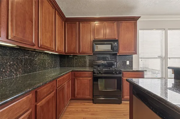 a kitchen with stainless steel appliances granite countertop a stove a sink and a microwave