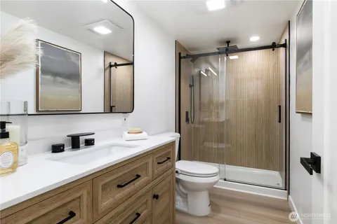 a bathroom with a shower sink vanity mirror and toilet